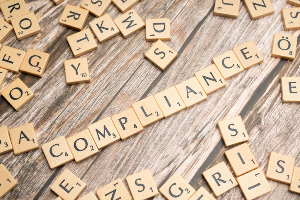 Holzbuchstaben bilden das Wort Compliance – Dokumentation für den AI Act im Marketing
