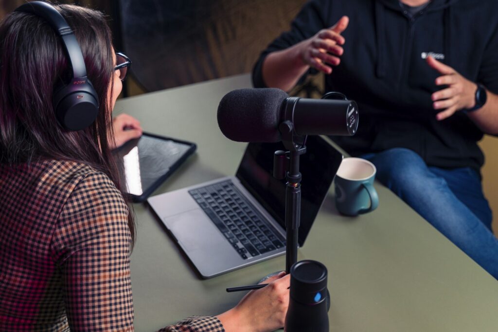 Podcast-Host und Gast im Gespräch mit Kopfhörern am Laptop – Audio als Format im Content Recycling