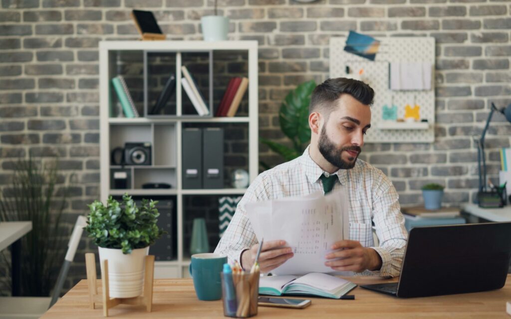 Mann am Schreibtisch mit Laptop und Unterlagen