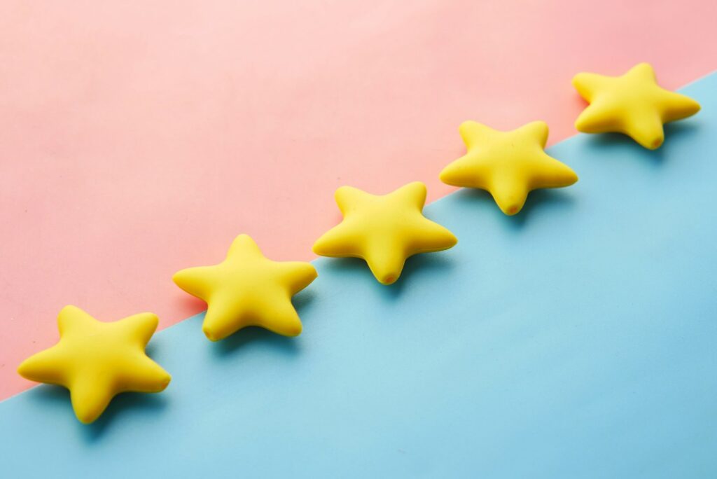 Reihe gelber Sterne auf blau-rosa Untergrund als Symbol für Bewertungen, mit denen du den Markenwert messen kannst