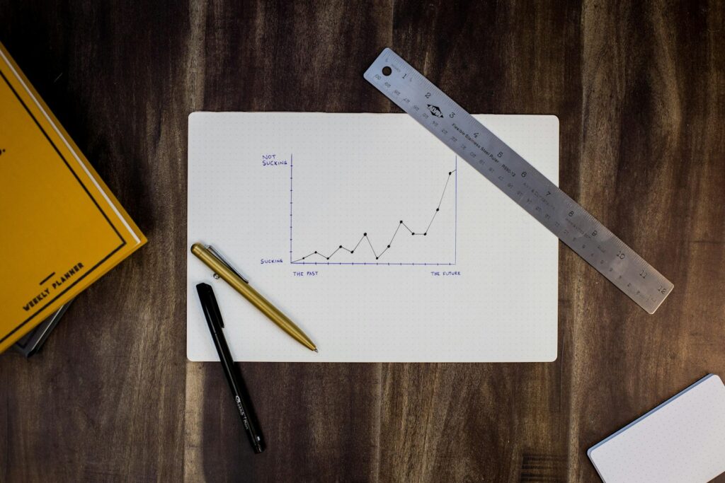Handgezeichnetes Liniendiagramm mit Lineal und Stiften auf Papier zeigt, wie du den Markenwert messen und Trends verfolgen kannst