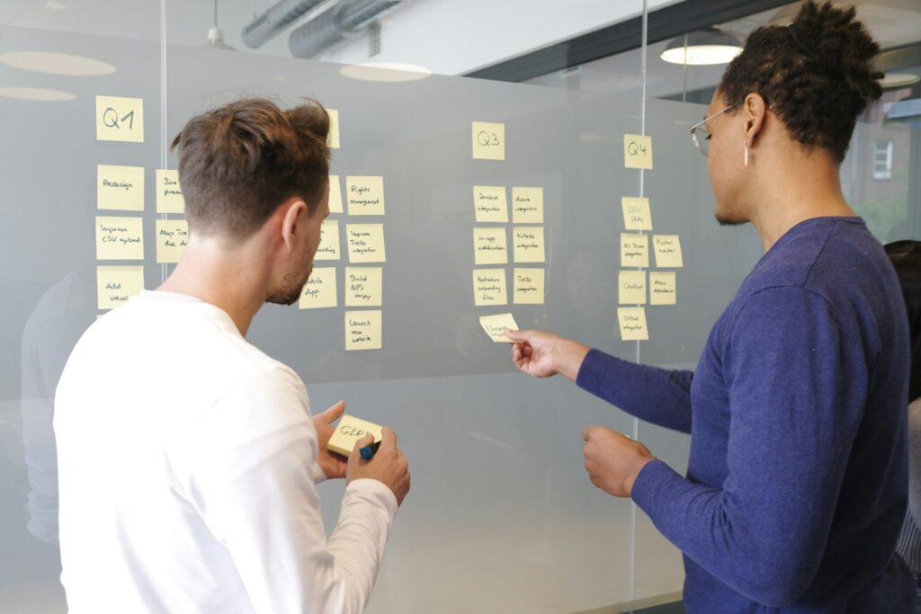 Zwei Personen planen mit gelben Haftnotizen an einer Glaswand eine Roadmap zu den Marketing Trends 2027