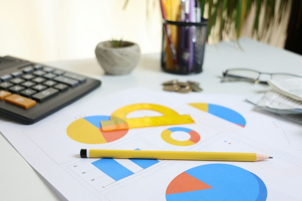 Schreibtisch mit Taschenrechner, Diagrammen und Bleistift beim Marketingbudget planen