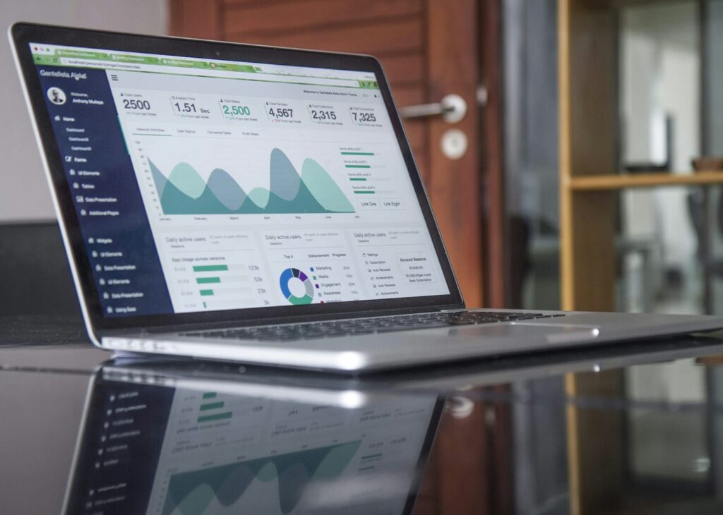 Laptop mit Statistiken auf einem Glastisch zur Auswertung, bevor du dein Marketingbudget planen kannst