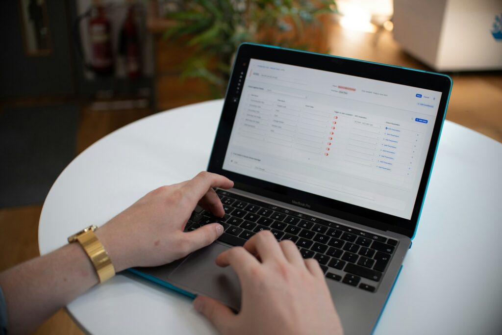 Hände tippen auf einem Laptop mit Tabelle, während die Marketingleitung das Budget prüft