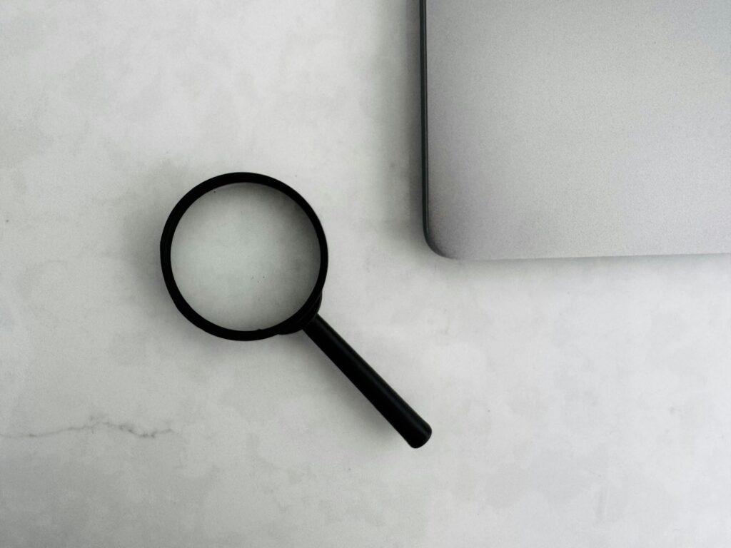Lupe neben einem Laptop als Symbol für den kritischen Blick auf Marketingstudien