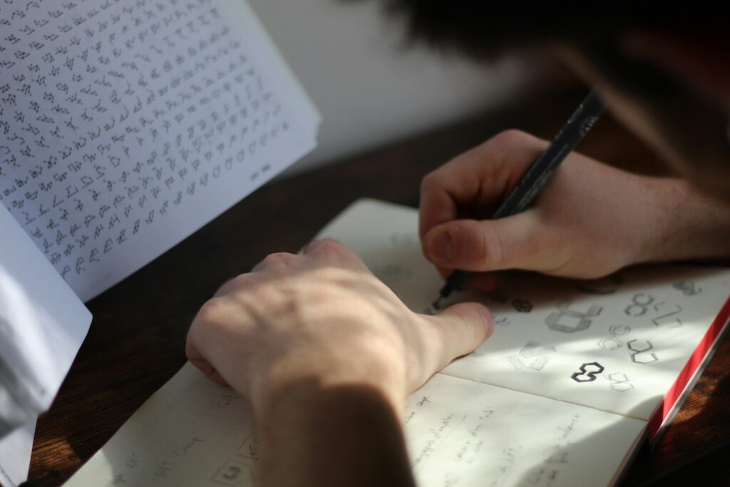 Mann skizziert mit Stift Logoentwürfe auf Papier am Holztisch, wenn Unternehmen ein Rebranding planen