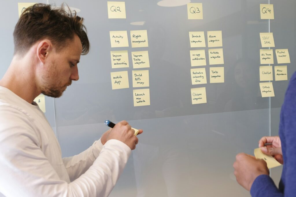 Mann schreibt am Whiteboard Prioritäten für das Quartal auf, um mit dem Team einen Redaktionsplan zu erstellen