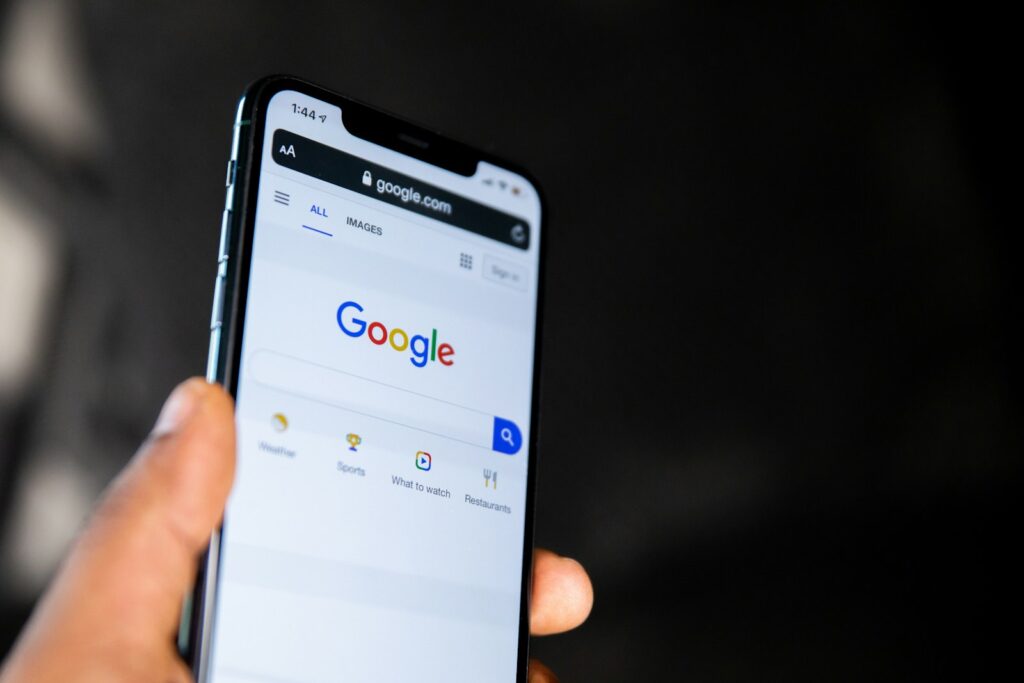 Hand hält ein Smartphone mit der Google-Startseite, auf der eine Zero-Click-Suche beginnen kann