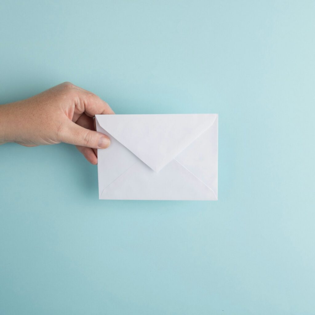 Person zeigt einen weißen Briefumschlag als Symbol für Newsletter, mit denen du die Zero-Click-Suche ausgleichst